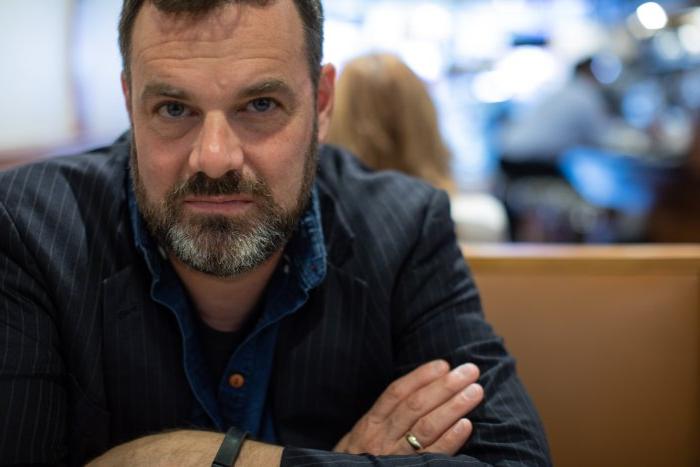 Headshot of Visiting Writer Grant Faulkner at a table with arms crossed.